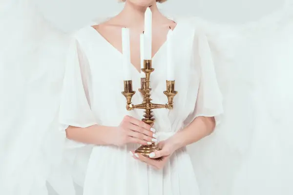 Ausschnitt eines weiblichen Engels von vorne, der einen vierstrahligen goldenen Kerzenleuchter hält